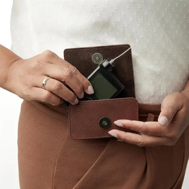 Leather insulin pump bag in use with secure magnetic closure and flexible mounting options.