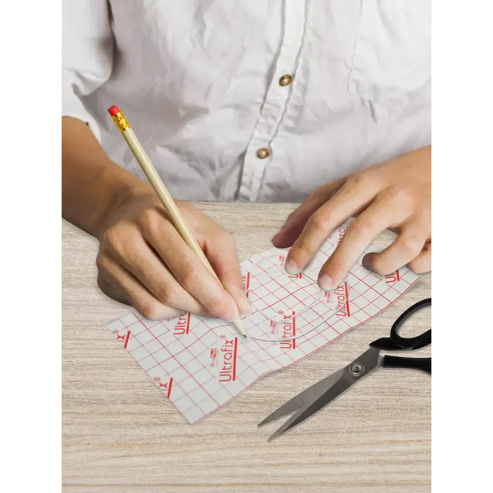 Insulin patch pump template being traced and cut for a personalized fit.