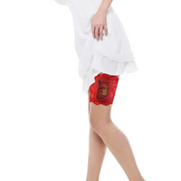 Red lace garter leg band securely holding an insulin pump, worn under a white dress